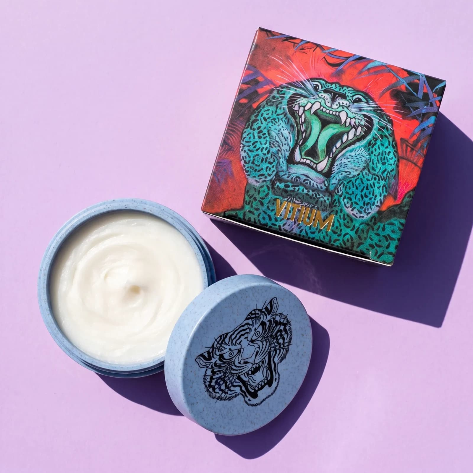 VITIUM Tattoo Butter 30ml open beside its tiger lid and illustrated box, from above on lilac
