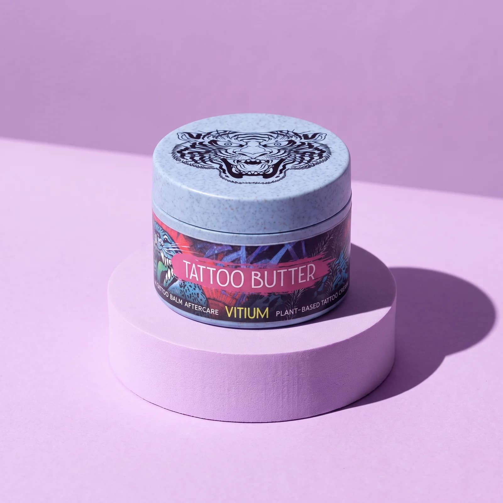 VITIUM Tattoo Butter 30ml jar with the tiger lid on a lilac plinth